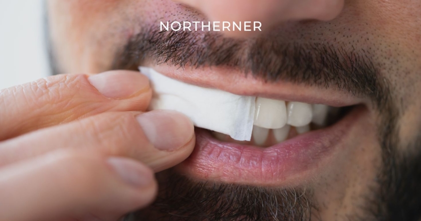 Jemand legt eine Nicotine Pouch unter die Lippe