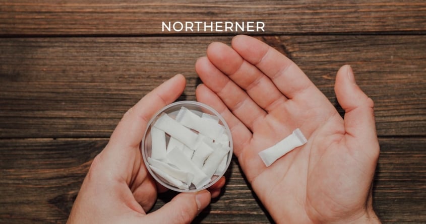 Eine Hand hält eine Dose Nicotine Pouches und einen Nikotinbeutel