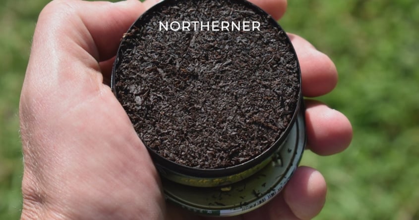 Eine Person hält eine Dose mit losem Snus in der Hand