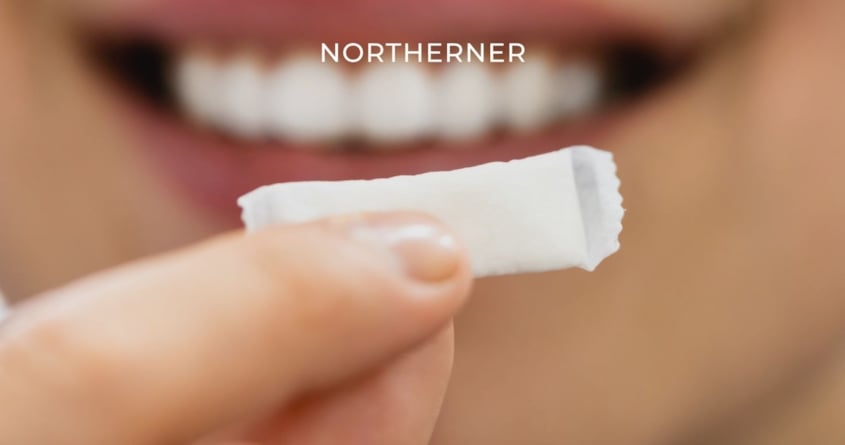 Jemand hält einen Snus zwischen den Fingern und lächelt