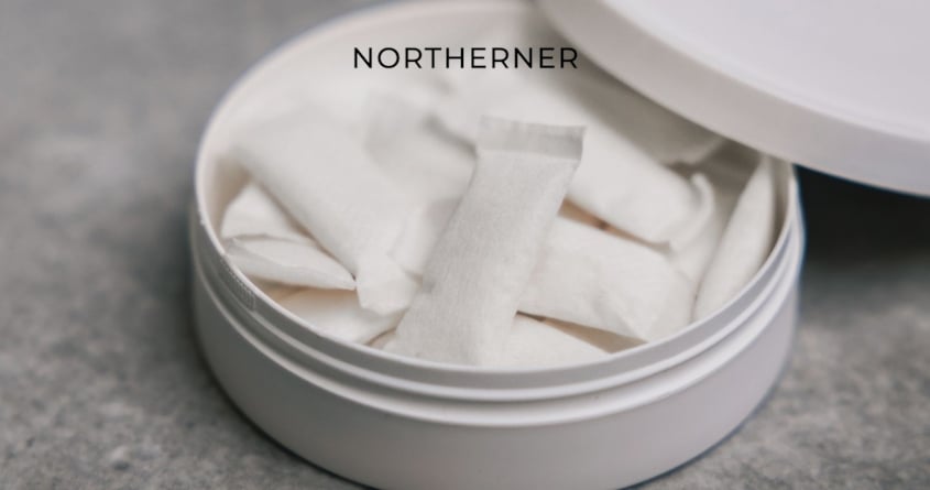 Eine Dose mit All-White-Snus liegt offen auf einem Tisch