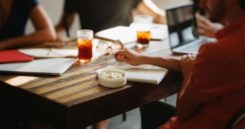 group of people sat at table with nicotine pouch can, for world snus day