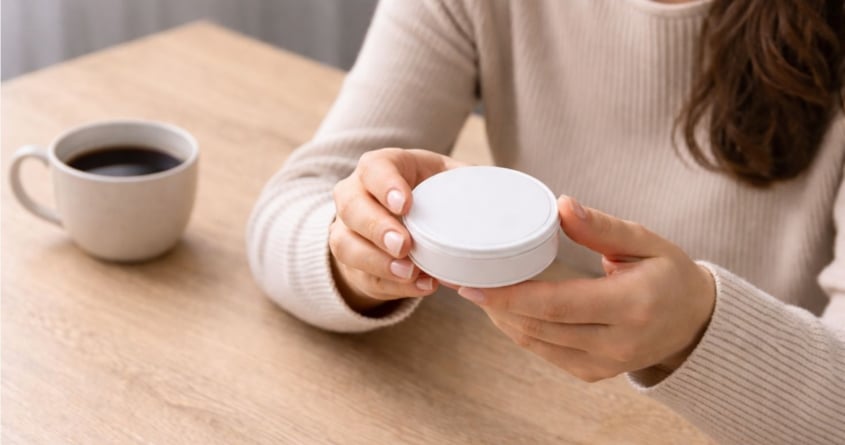 Woman contemplates nicotine pouch can, as a new nicotine pouch user
