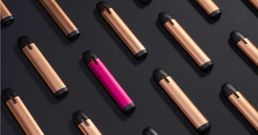 Several vapes laying on a dark surface