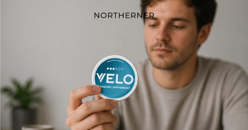 A man holds up and observes a VELO Freezing Peppermint snus can