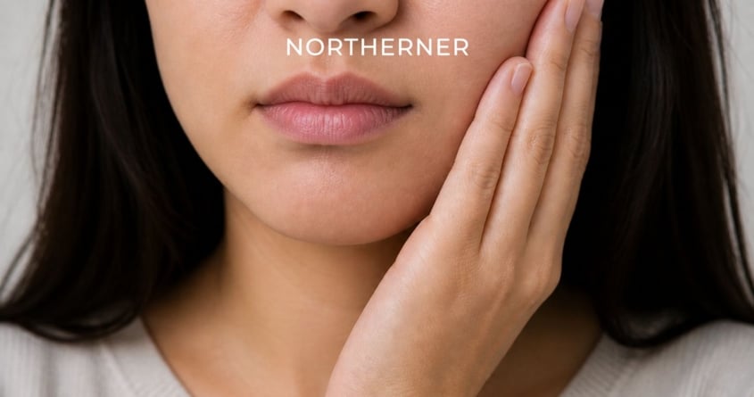 Woman holds her cheek, as if experiencing a sensation