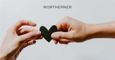 two hands exchanging a black paper heart
