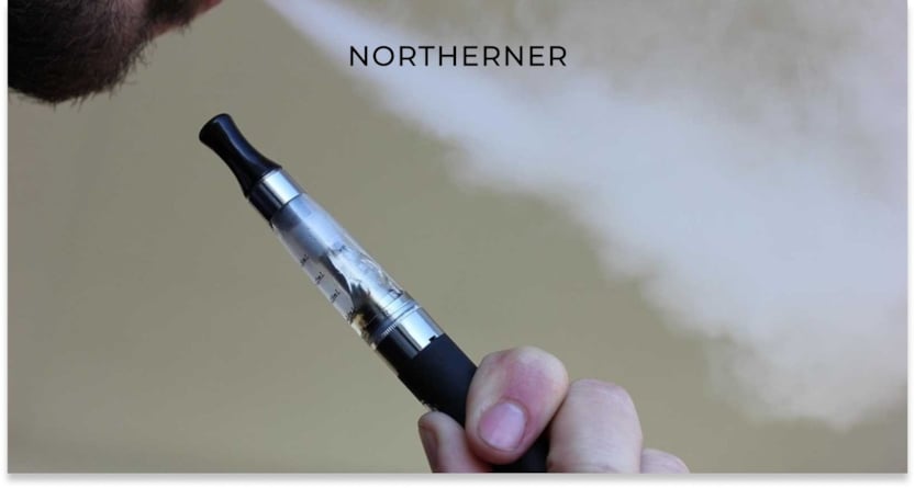 person exhaling from a vape that they hold in their hand