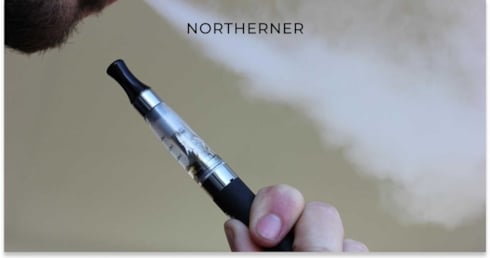 person exhaling from a vape that they hold in their hand