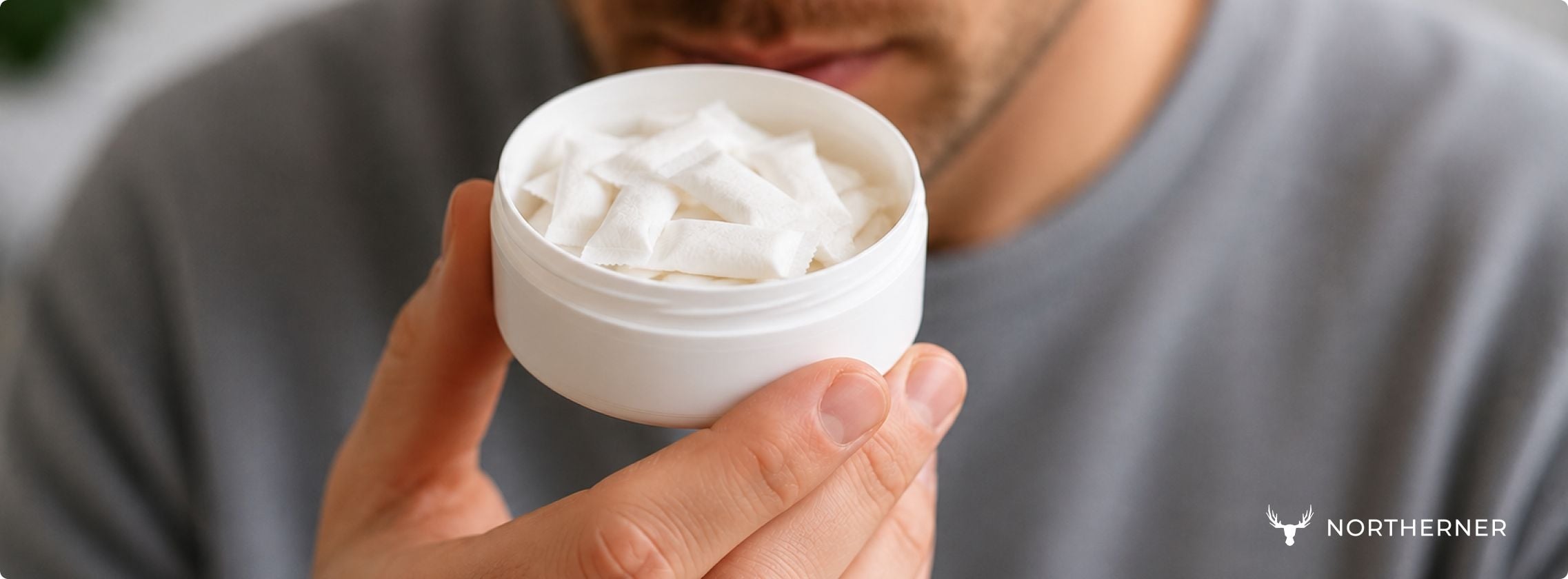 a person smells an open can of nicotine pouches